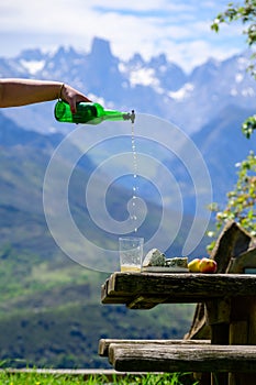 Pouring from high height of natural Asturian cider made fromÂ fermented apples, Asturian cabrales cow blue cheese with view on